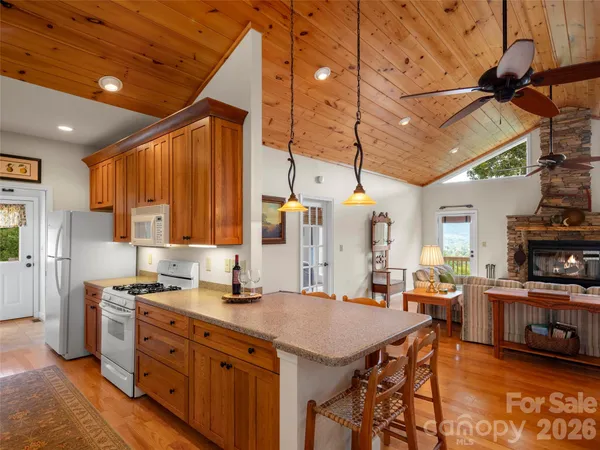 a kitchen with stainless steel appliances kitchen island granite countertop a table chairs in it and a wooden floor