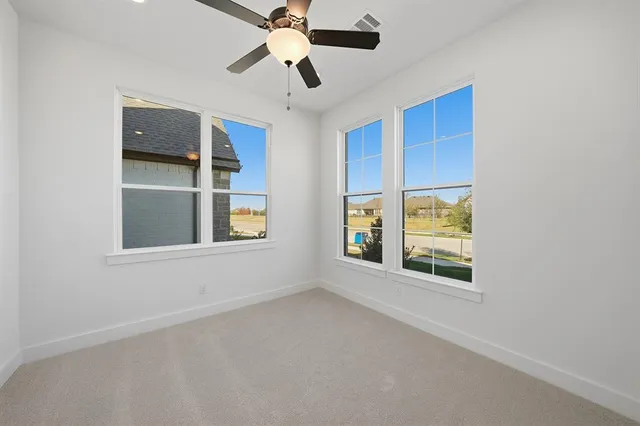 an empty room with windows and fan