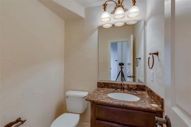 a bathroom with a granite countertop sink vanity mirror and toilet