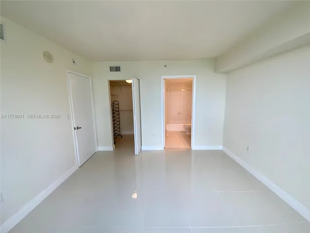 a view of an empty room with closet and a window