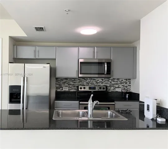 a kitchen with a refrigerator and a stove top oven