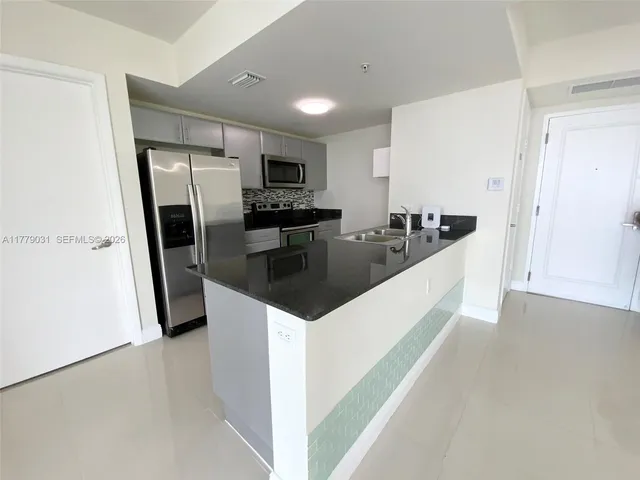 a kitchen with stainless steel appliances a sink a stove a refrigerator a counter top space and cabinets