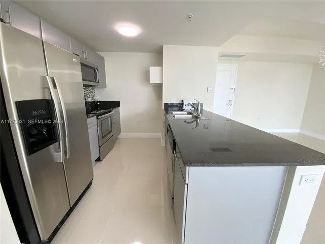 a kitchen with stainless steel appliances a refrigerator a sink a stove and a refrigerator