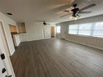 a view of a hallway with wooden floor and a kitchen