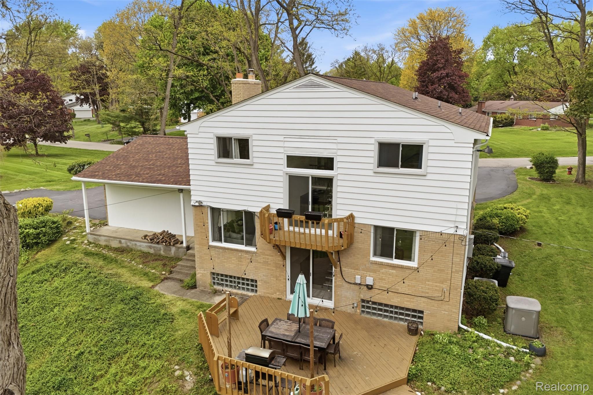 47129 Dunsany Road Northville, MI 48167 - Photo 48 of 49 Rear view of house featuring a yard, outdoor dining space, brick siding, a chimney, and a wooden deck