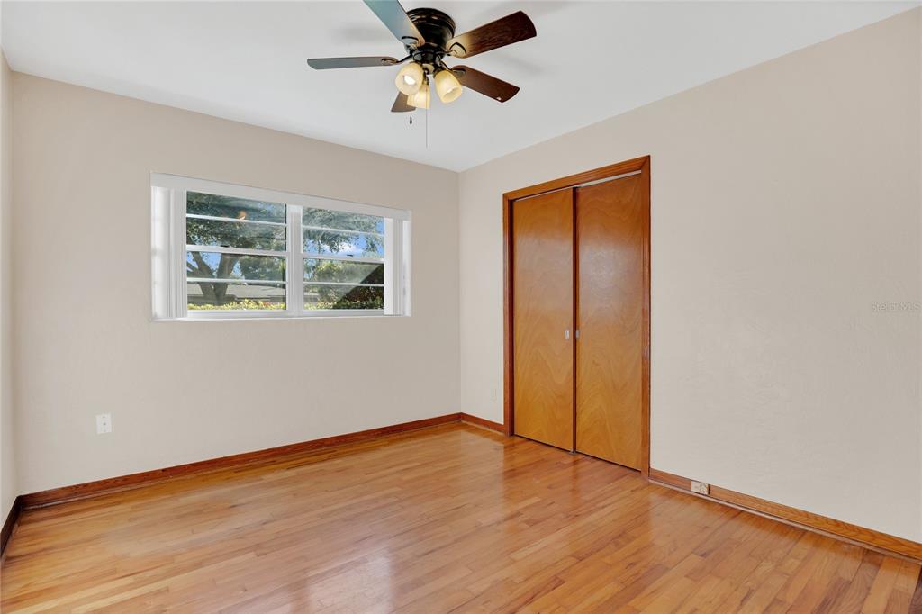 2807 Nancy Street Orlando, FL 32806 - Photo 13 of 27 an empty room with wooden floor chandelier fan and windows