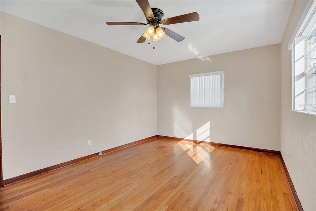 2807 Nancy Street Orlando, FL 32806 - Photo 16 of 27 an empty room with wooden floor chandelier fan and windows