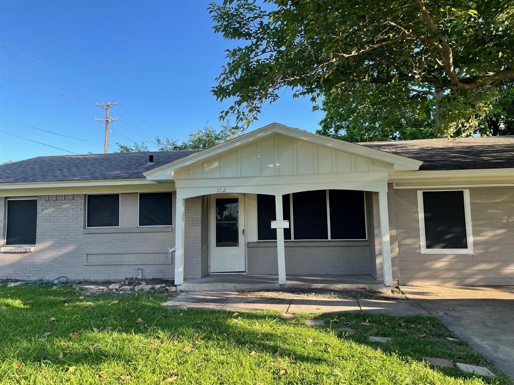 102 Roma Drive Garland, TX 75041 - Photo 2 of 9 Single-story residence featuring a covered front porch with white columns, light gray brick and siding, a dark gray shingle roof, and a white front door
