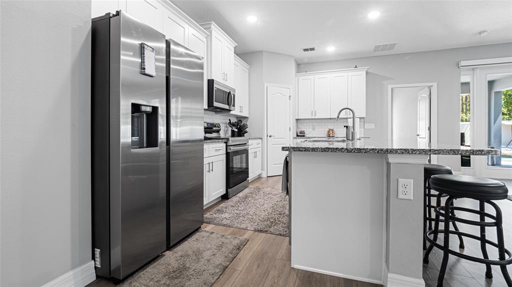 8007 Southwest 135th Loop Ocala, FL 34473 - Photo 13 of 47 a kitchen with stainless steel appliances granite countertop a refrigerator a sink a stove a table and chairs