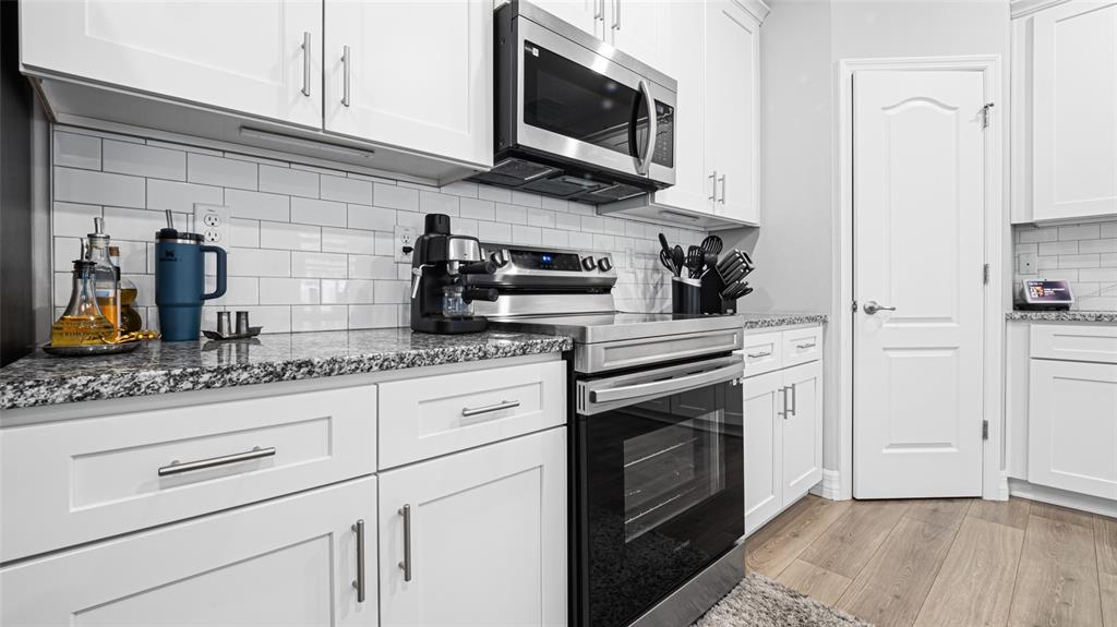 8007 Southwest 135th Loop Ocala, FL 34473 - Photo 14 of 47 a kitchen with granite countertop white cabinets stainless steel appliances and wooden floor