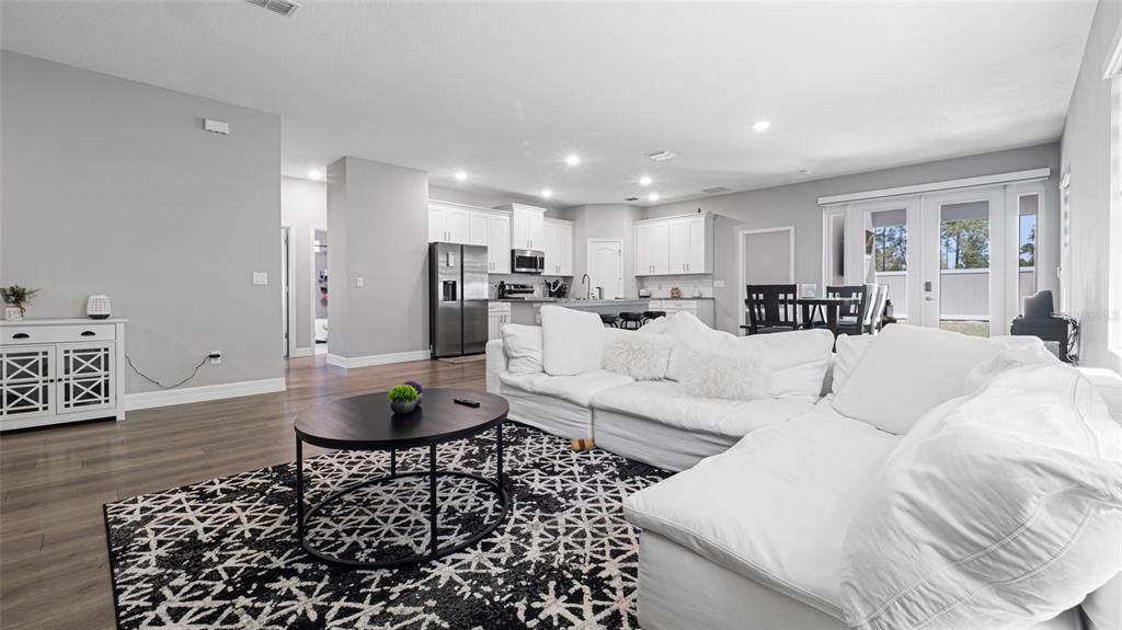 8007 Southwest 135th Loop Ocala, FL 34473 - Photo 16 of 47 a living room with furniture and a dining table with wooden floor