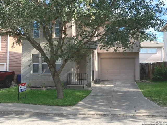 a front view of a house with a garden and trees