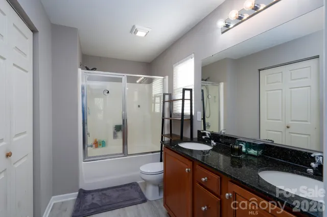 a bathroom with a granite countertop sink toilet a mirror a vanity and shower