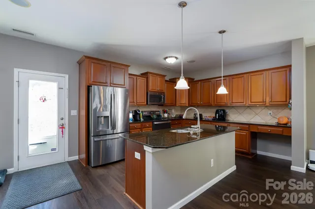a kitchen with stainless steel appliances granite countertop a sink a stove and refrigerator