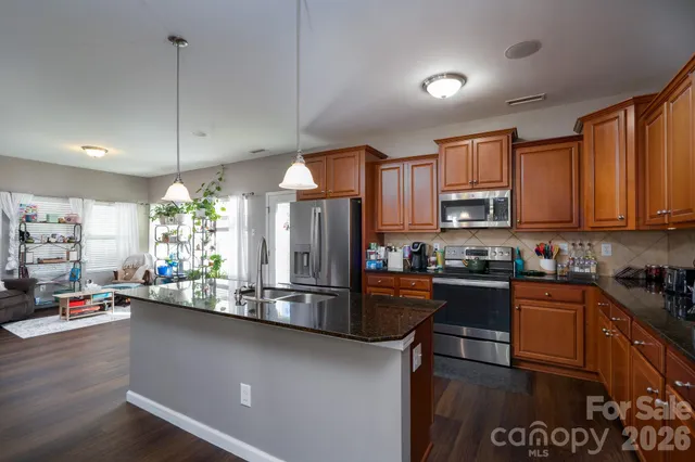 a kitchen with stainless steel appliances granite countertop a sink a stove top oven a counter space and cabinets