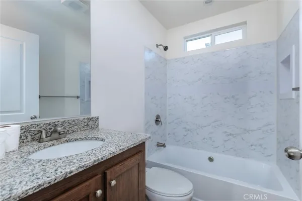 a bathroom with a granite countertop sink a toilet and bathtub