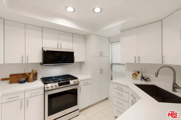 a kitchen with a sink stove and white cabinets