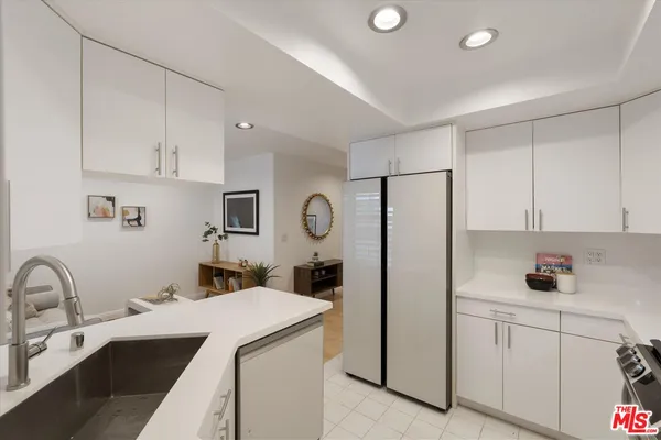 a kitchen with a sink dishwasher and white cabinets with wooden floor