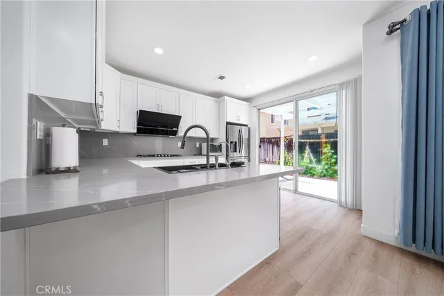 a kitchen with stainless steel appliances a sink a stove a microwave a refrigerator and cabinets