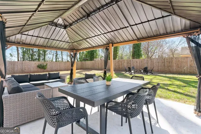 a view of patio with a table and chairs under an umbrella with a small yard