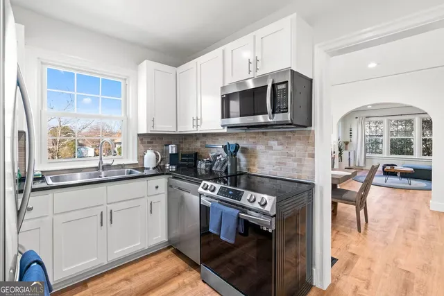 a kitchen with stainless steel appliances granite countertop a stove top oven a sink a dining table and chairs