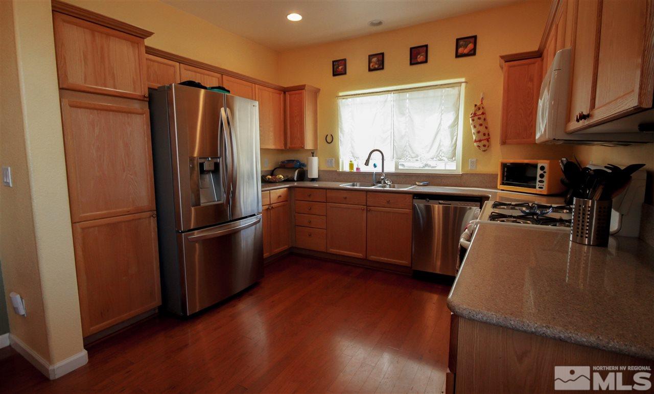 1707 River Gorge Court Reno, NV 89521 - Photo 6 of 18 a kitchen with stainless steel appliances granite countertop a refrigerator a sink dishwasher a stove with wooden floor and cabinets