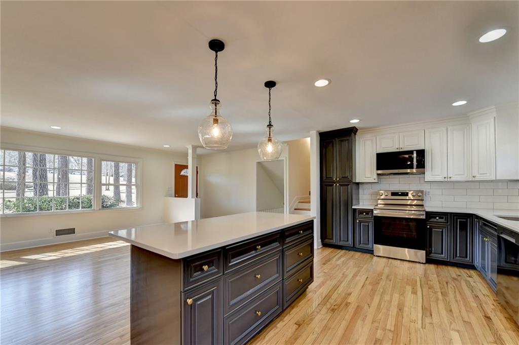 3463 Northlake Way Atlanta, GA 30340 - Photo 26 of 73 a large kitchen with stainless steel appliances kitchen island granite countertop a stove a sink dishwasher a refrigerator and a kitchen island with wooden floor
