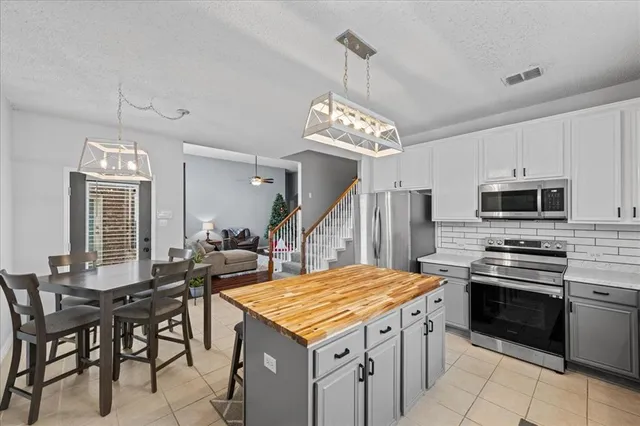 a kitchen with stainless steel appliances granite countertop a stove a refrigerator a kitchen island a sink dishwasher a dining table and chairs with wooden floor