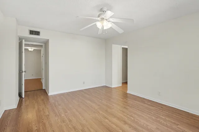 an empty room with wooden floor and a ceiling fan