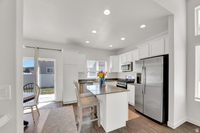 6120 North Sheps Ridge Road Eagle Mountain, UT 84005 - Photo 6 of 43 Contemporary kitchen featuring white cabinetry, stainless steel appliances, an island with countertop seating, recessed lighting, and wood-finish flooring