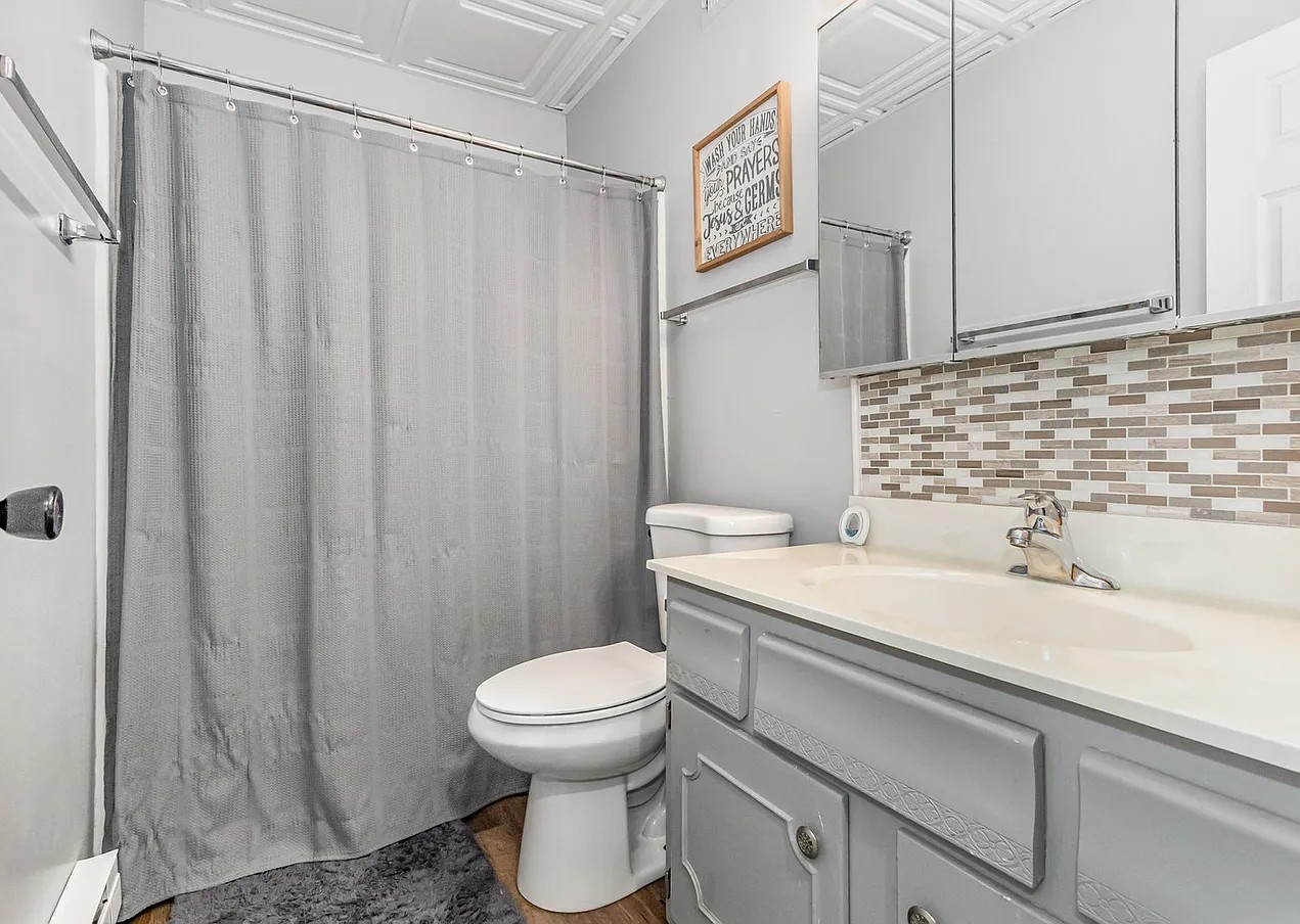 1420 Woodbridge Road, Unit 1E Joliet, IL 60436 - Photo 10 of 17 a bathroom with a sink a toilet and shower curtain