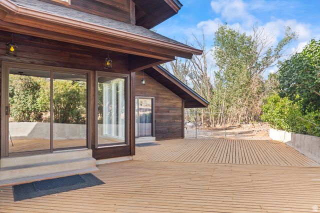 460 Omni Point Road Central Valley, UT 84754 - Photo 69 of 101 Expansive outdoor decking crafted from light wood, featuring a concrete retaining wall and mature surrounding foliage