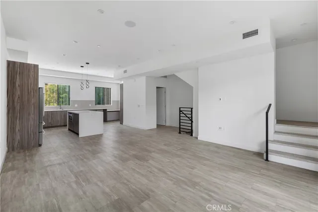 a view of a big room with wooden floor and windows