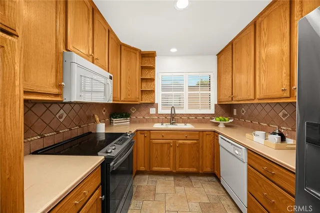 a kitchen with a sink a stove top oven cabinets and a window