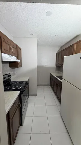 a kitchen with granite countertop a stove a sink and a refrigerator