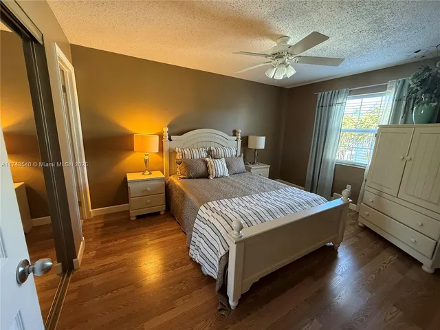a bedroom with a bed and a large window with wooden floor