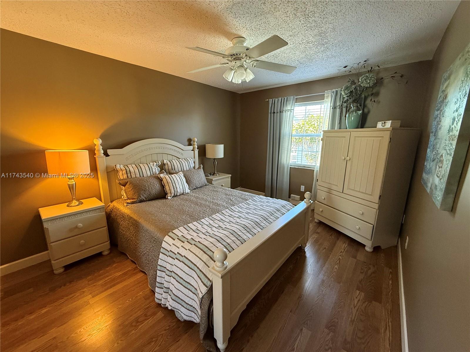 609 Waterside Drive, Unit 609 Hypoluxo, FL 33462 - Photo 9 of 33 a bedroom with a bed and a large window with wooden floor