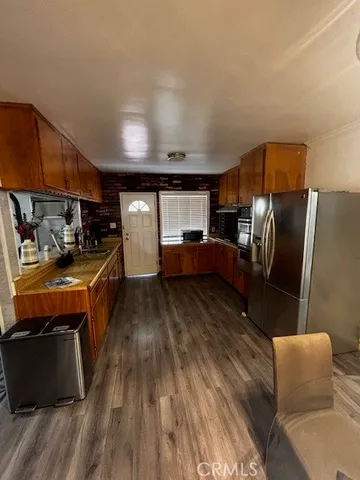 a kitchen with stainless steel appliances kitchen island granite countertop a refrigerator a stove a sink dishwasher and wooden cabinets with wooden floor