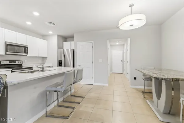 a large kitchen with stainless steel appliances a stove a sink dishwasher and a refrigerator with wooden floor