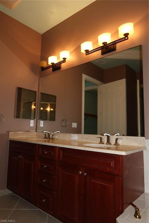 7168 Lemuria Circle, Unit 1701 Naples, FL 34109 - Photo 23 of 39 Dual vanity with rich wood cabinetry and a light-toned countertop, featuring two integrated sinks and brushed nickel faucets