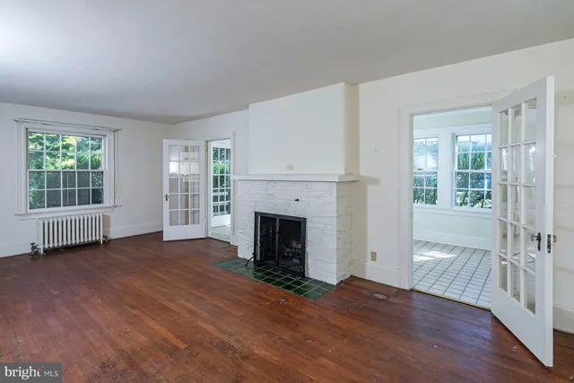 an empty room with wooden floor fireplace and windows
