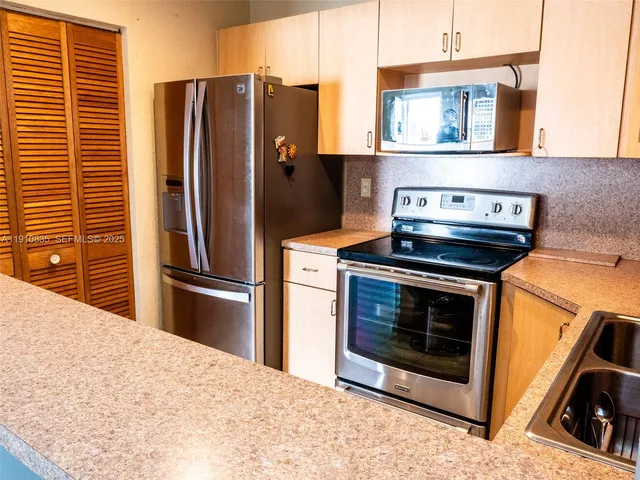 a kitchen with stainless steel appliances kitchen island a stove a refrigerator and cabinets