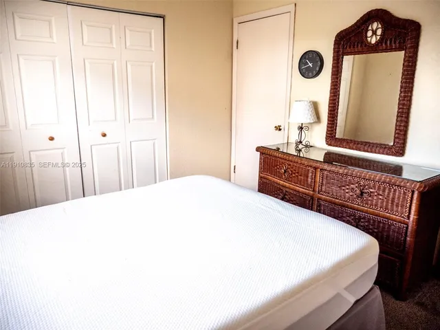 a spacious bedroom with a bed a mirror and a window