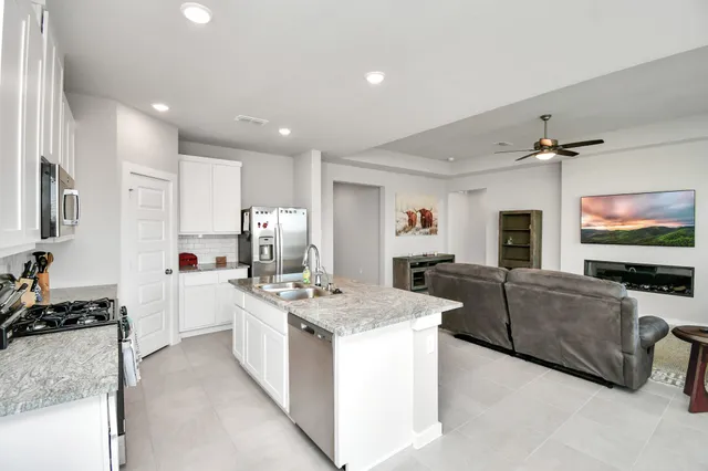 a large kitchen with stainless steel appliances a stove a sink dishwasher and a refrigerator with wooden floor