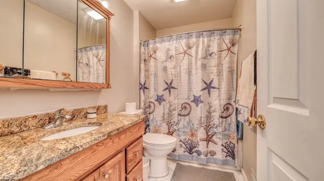 a bathroom with a granite countertop sink a toilet and a shower curtain