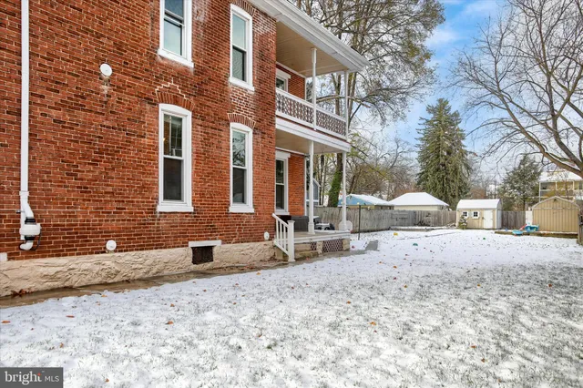 a front view of a house with a yard covered with snow and trees