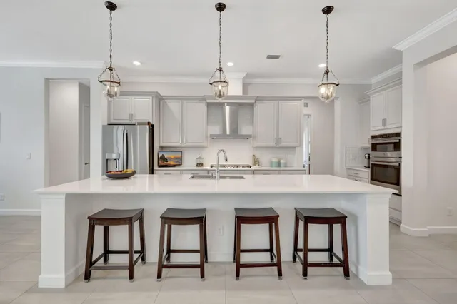 a kitchen with stainless steel appliances a stove a sink a refrigerator and white cabinets