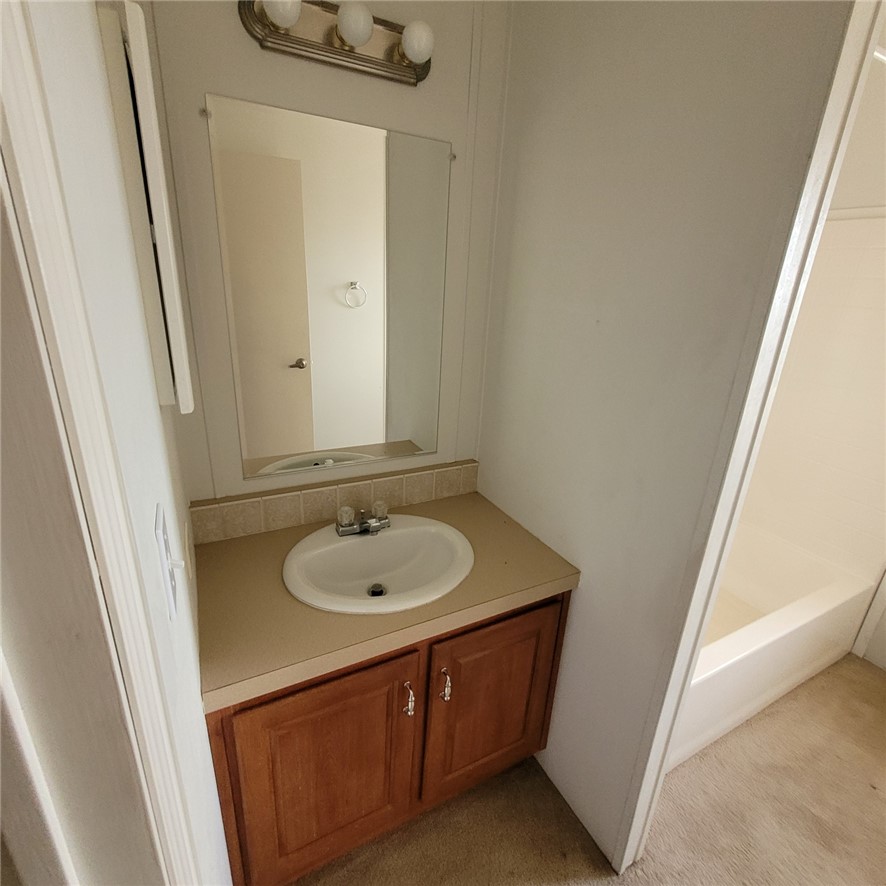 9732 2nd Street Chloride, AZ 86431 - Photo 25 of 28 Bathroom vanity with a white basin sink, chrome faucet, a large mirror, and overhead lighting
