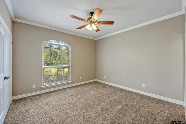 an empty room with ceiling fan and window