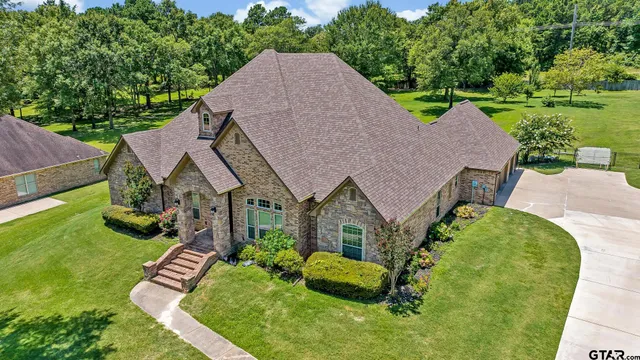a aerial view of a house in a big yard with potted plants
